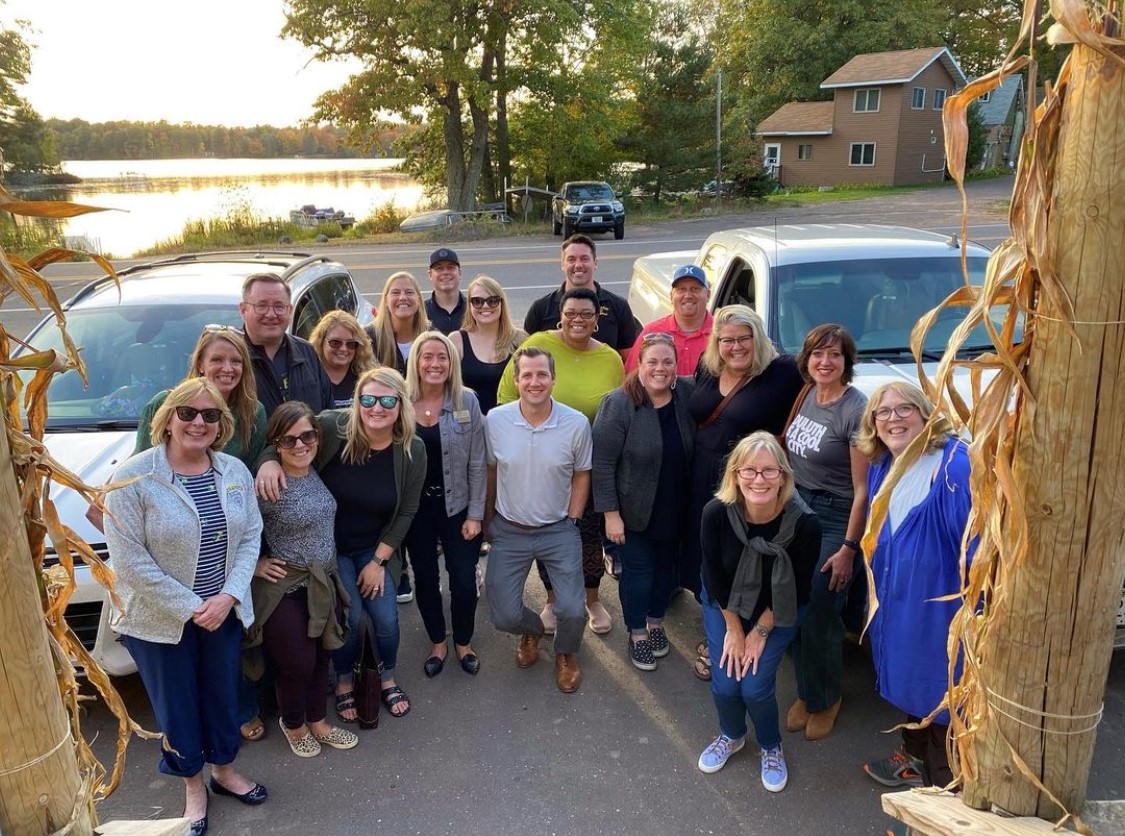 People standing in a driveway in front of a lake