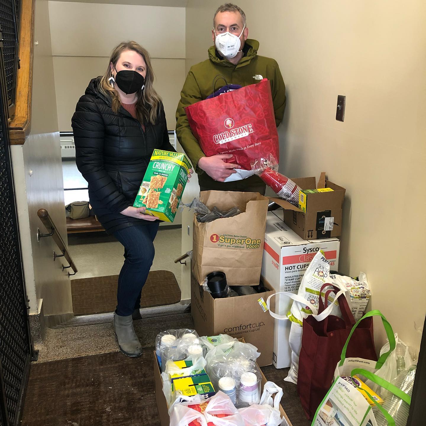 People holding up groceries in a hallway