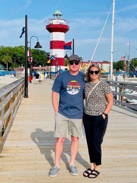 couple on a boardwalk in front of a lighthouse