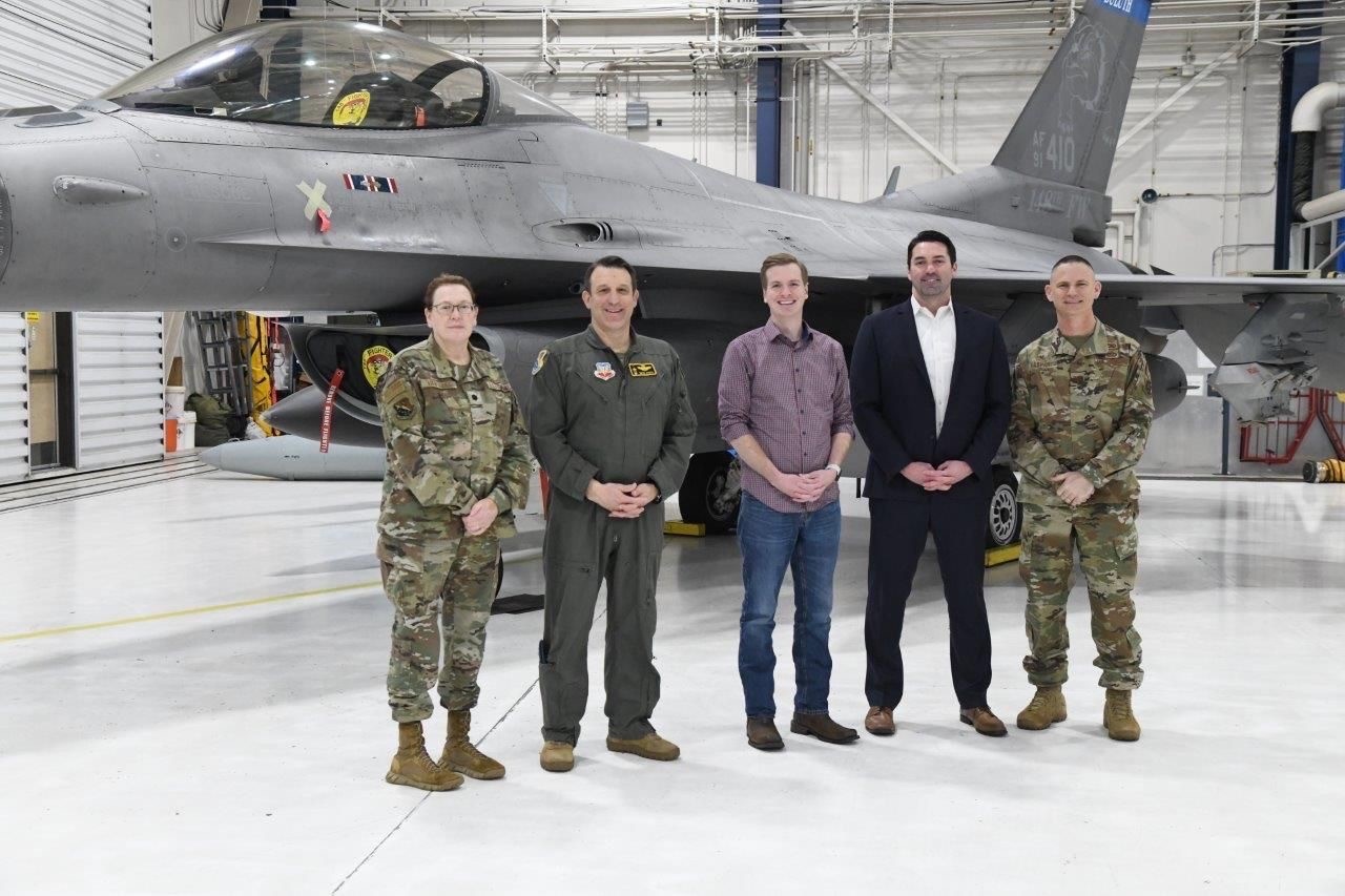 Group of people standing next to a fighter jet