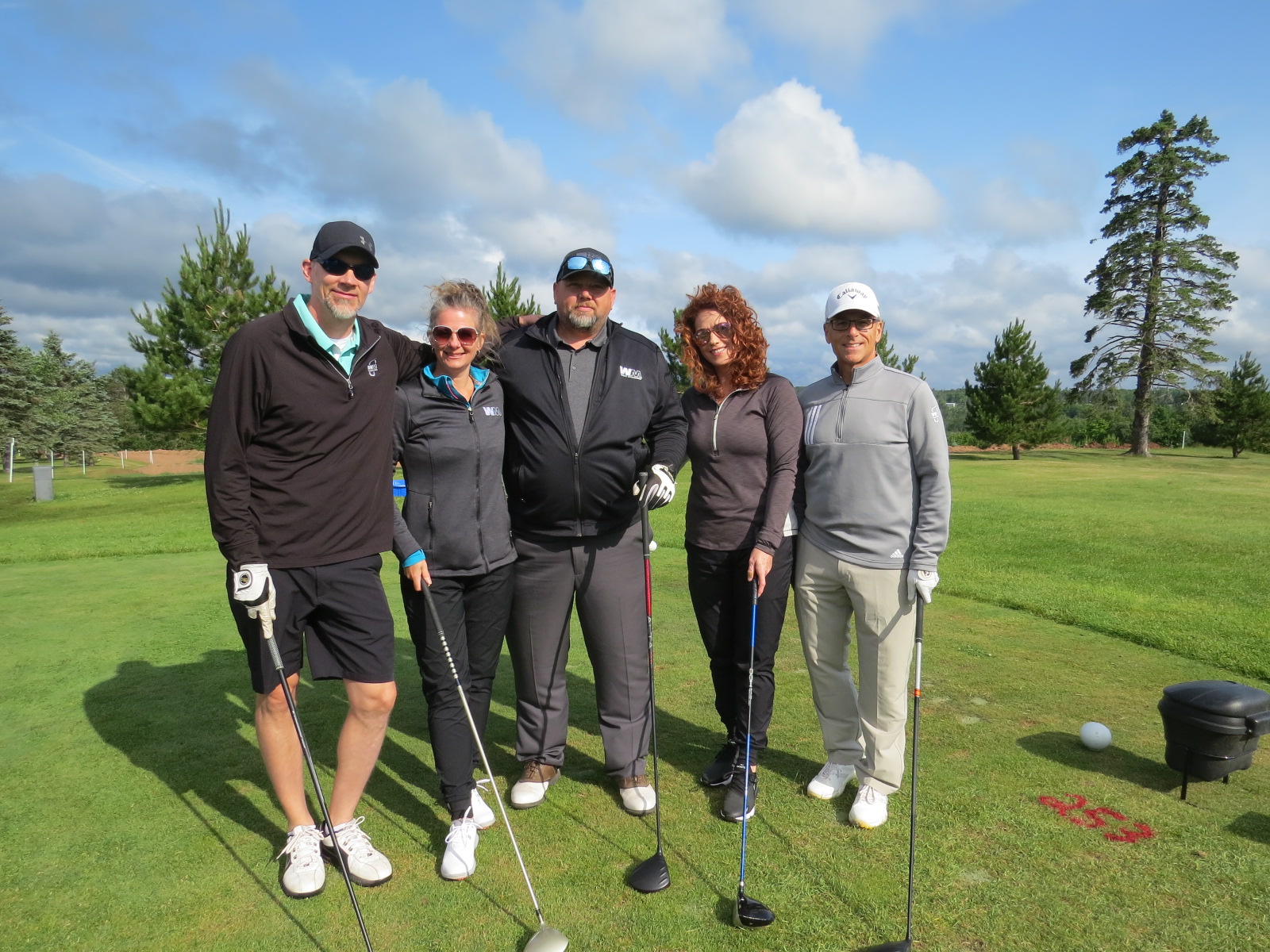 Five people smiling for a photo on a golf course